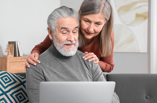 retired couple looking at a laptop screen and smiling