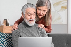 retired couple looking at a laptop screen and smiling