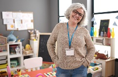 teacher standing in a classroom, smiling at camera