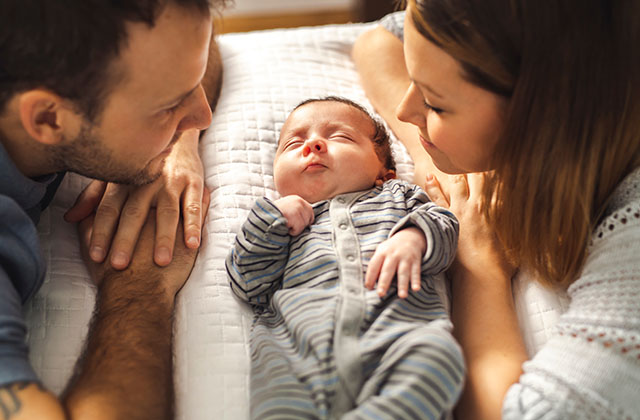 a couple looking adoringly at their newborn child