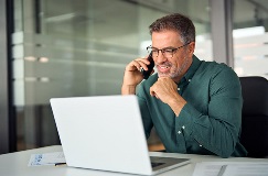 man using laptop computer and talking on phone