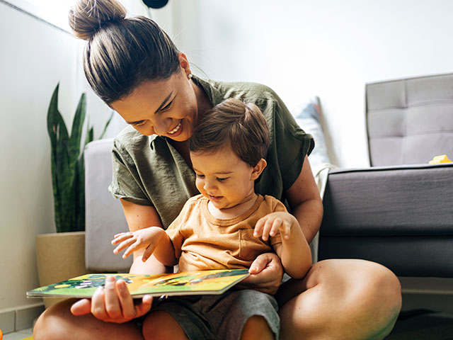a mother reading a book with her toddler on her lap