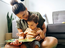a mother reading a book with her toddler on her lap