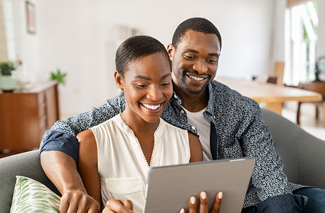a smiling couple view a tablet