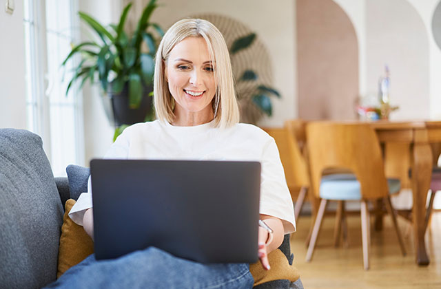 woman reclining on couch while using a laptop computer