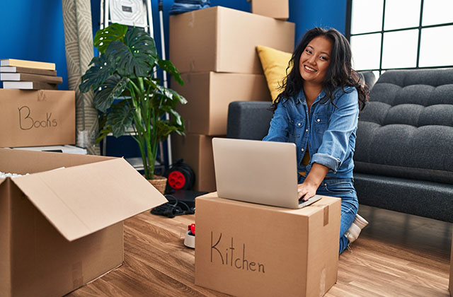 woman working on laptop with moving boxes in the background