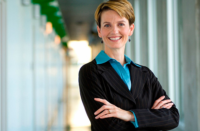 middle-aged woman posing in a school hallway, smiling