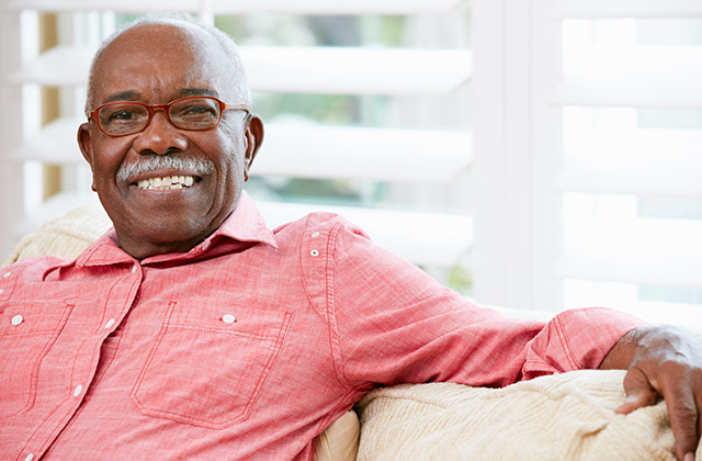 older man sitting on a couch, smiling