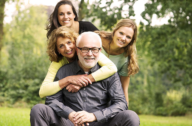 middle-aged couple posing with teenage daughters in an outdoor setting