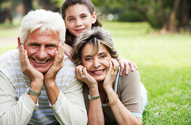 older couple posing for a photo outside with their granddaughter