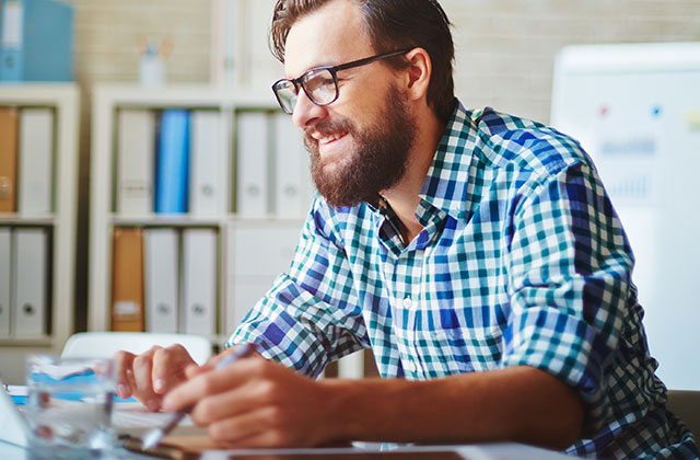 young man wearing glasses sitting at desk